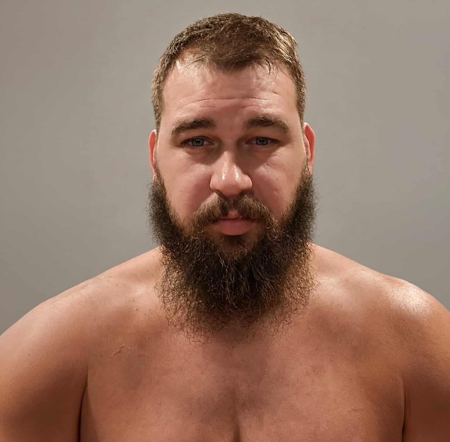 Close-up of a sumo wrestler with a beard and short hair.