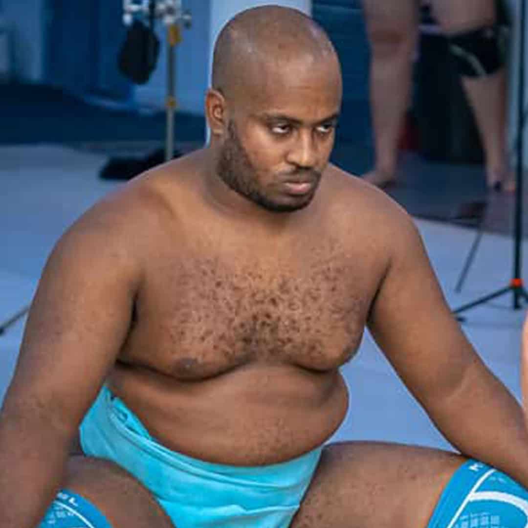 Sumo wrestler sitting on the mat, focused and ready.