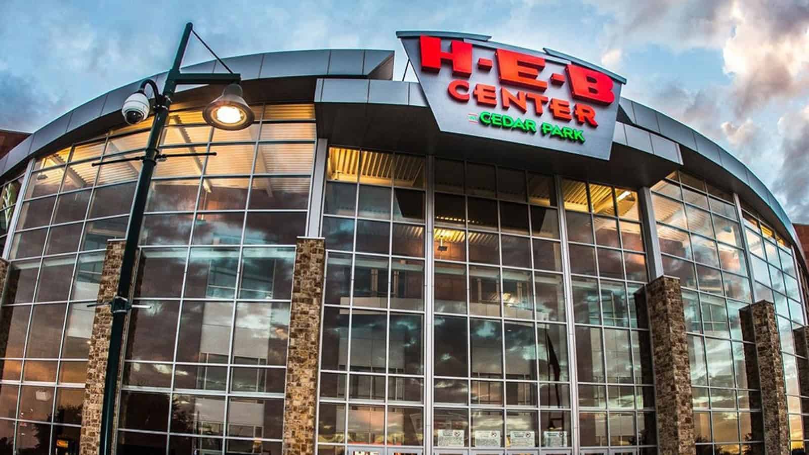 Exterior view of H-E-B Center at Cedar Park with glass facade and cloudy sky.
