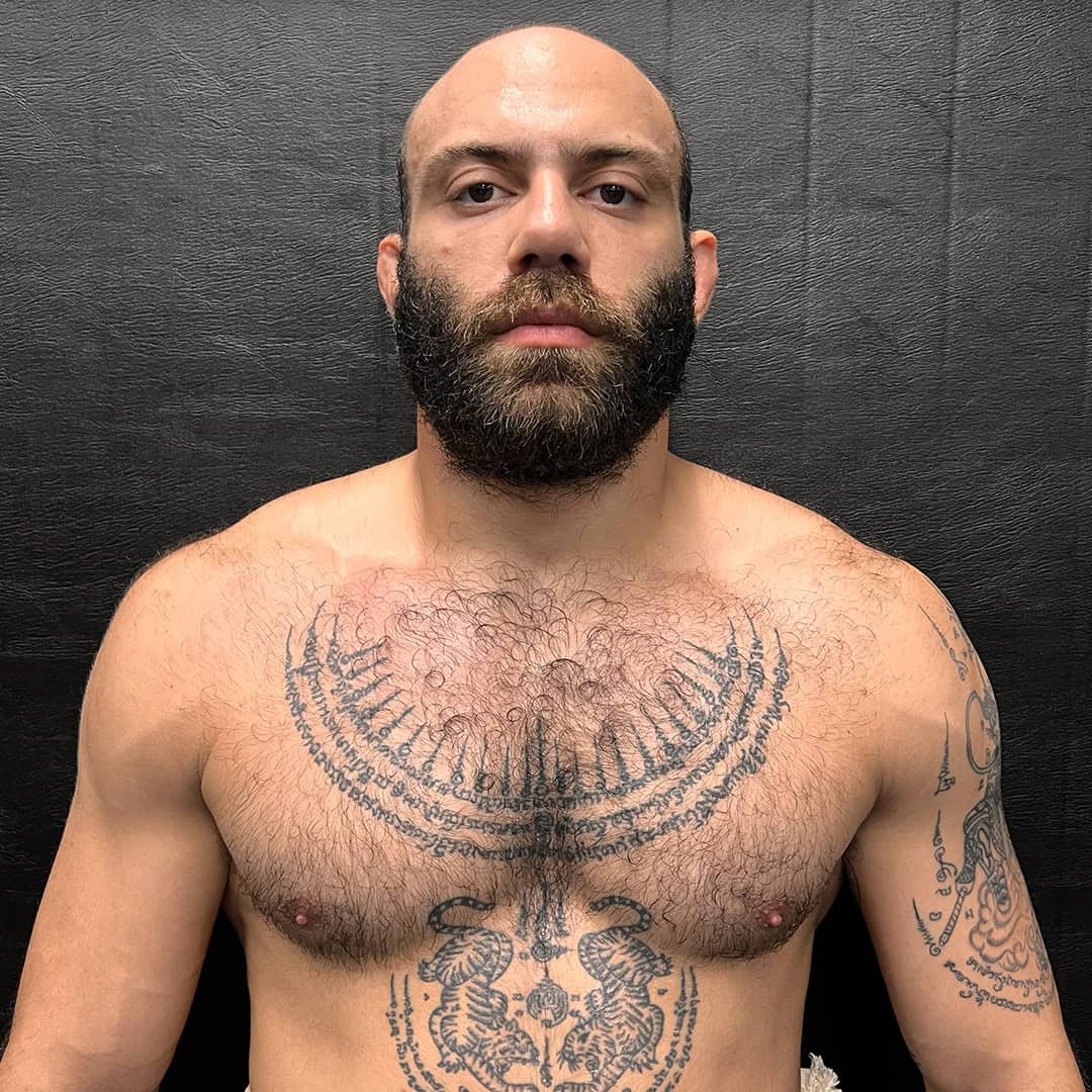 Sumo wrestler with a beard and tattoos on chest and arm.