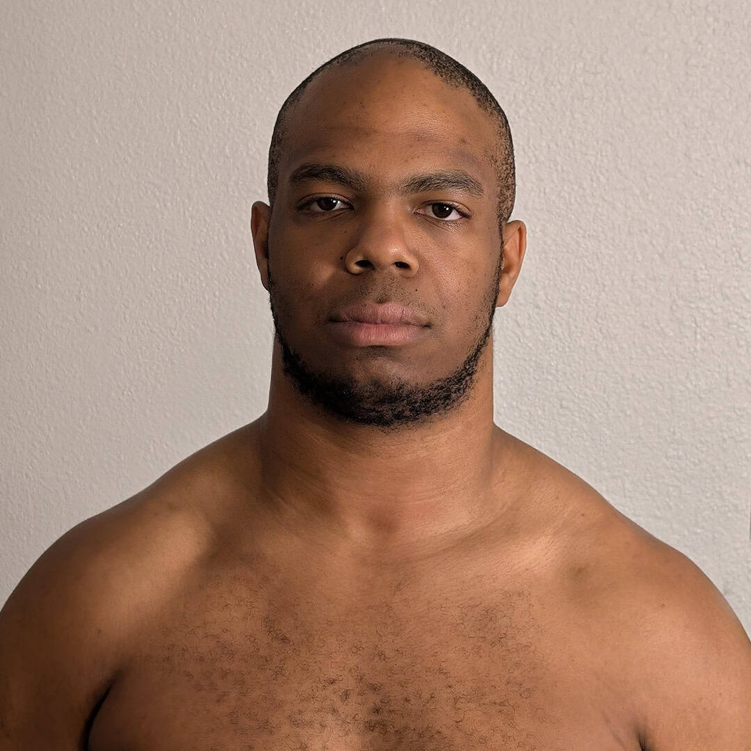 Sumo wrestler with serious expression, bare shoulders, and short hair.
