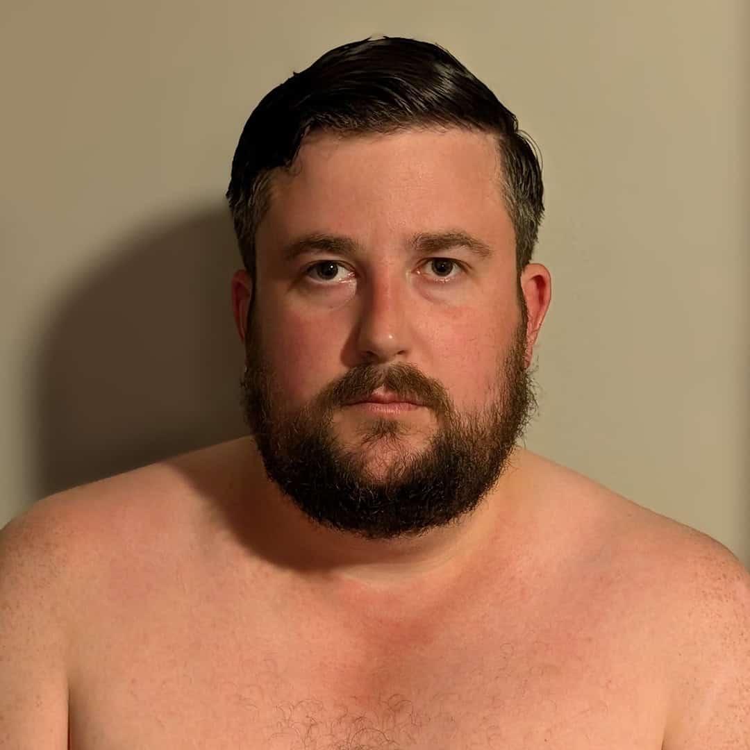 Portrait of a man with dark hair and beard, looking at the camera.