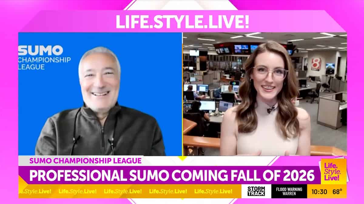 Two news anchors in a newsroom with Sumo Championship League graphics.