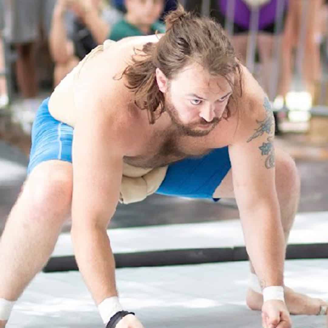 Sumo wrestler in stance on the ring floor.