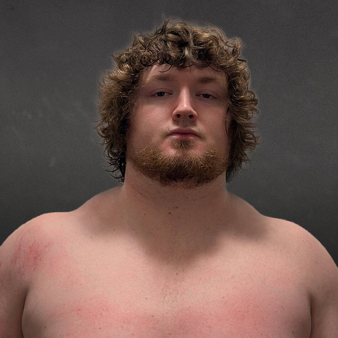 Close-up of a sumo wrestler with curly hair and beard.