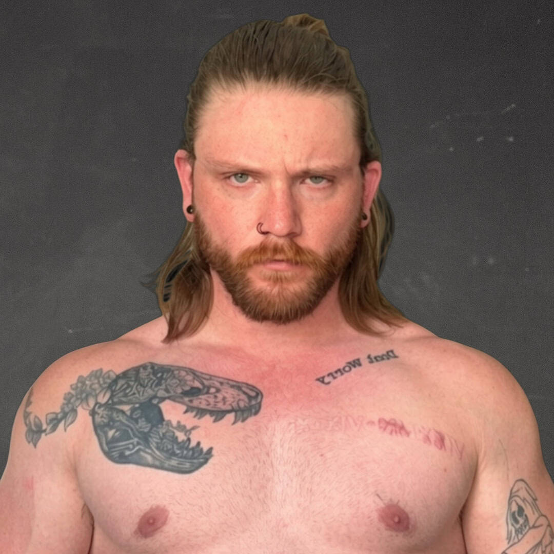 Man with long hair, beard, and tattoos on chest and arm.