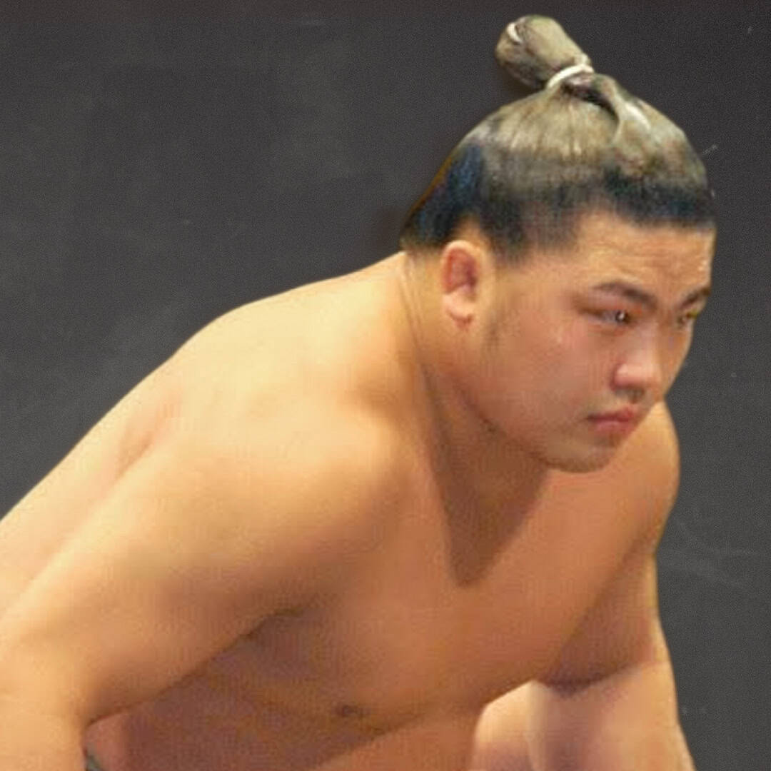 Sumo wrestler with topknot hairstyle looking focused.