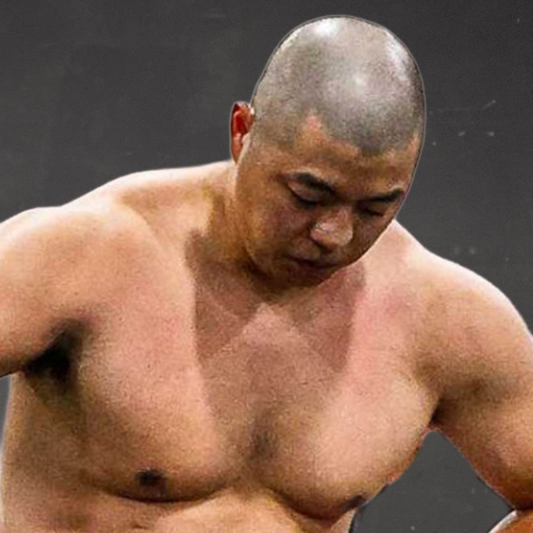 Sumo wrestler with shaved head and muscular build.