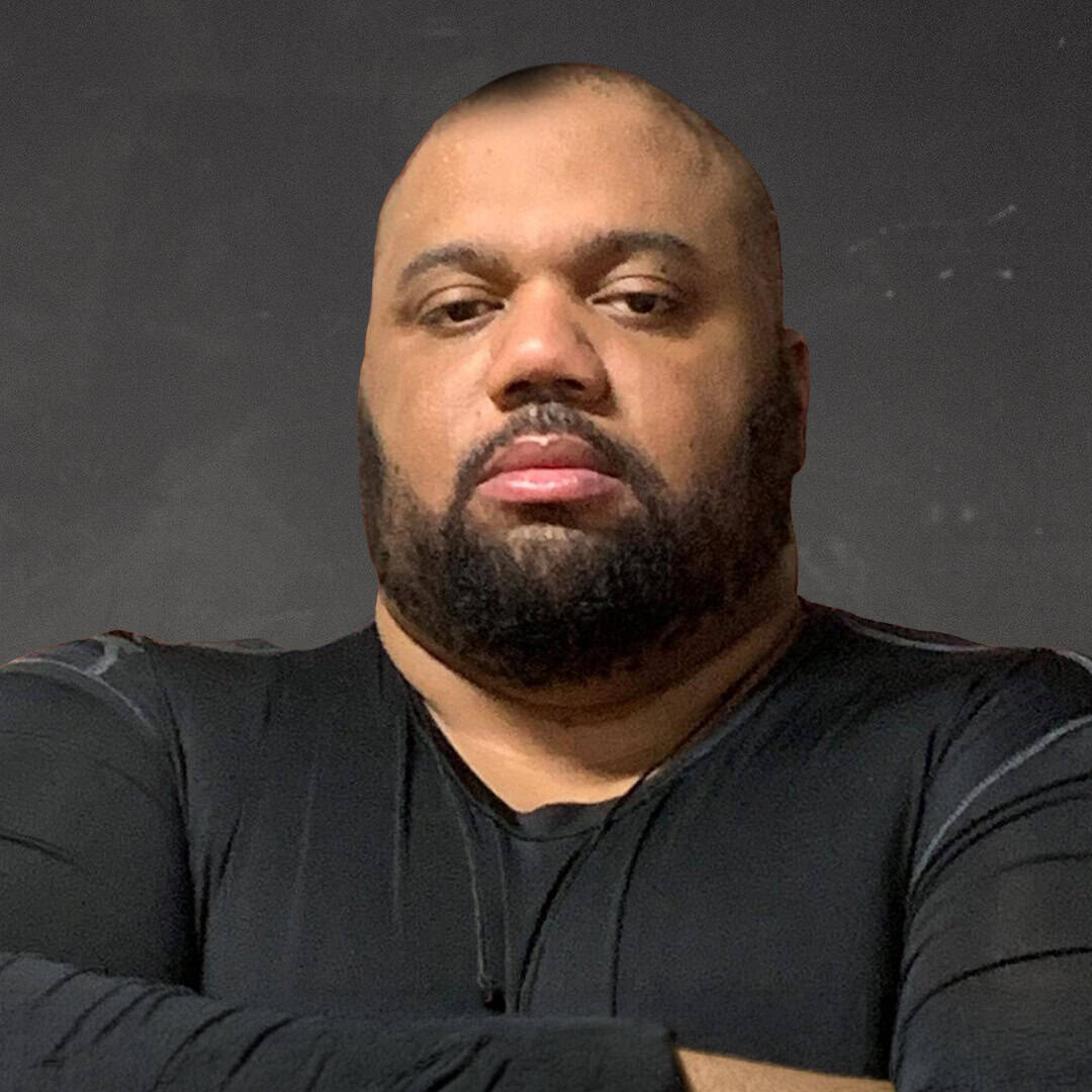 Portrait of Theodore Mitchell with crossed arms and serious expression.
